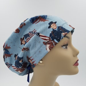 May include: A blue surgical scrub hat with a pattern of American flags and men in military uniforms. The hat has a blue tie.
