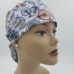 May include: A blue and white patterned surgical scrub hat with a design of vintage bicycles. The hat has a tie on the back.