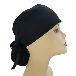 May include: A black scrub hat with a ponytail opening and a black ribbon tie. The hat is made of a soft, comfortable fabric and is designed to keep hair out of the way.