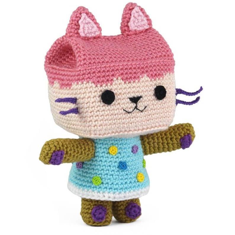 Op de afbeelding: Een gehaakt knuffeltje in de vorm van een kat met roze oren, een blauw-wit geblokt jurkje en bruine armen en benen.