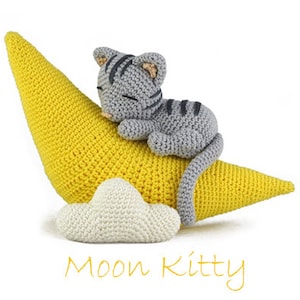Könnte beinhalten: Eine graue gehäkelte Katze schläft auf einem gelben gehäkelten Halbmond mit einer weißen gehäkelten Wolke. Der Text "Moon Kitty" steht unter dem Mond.