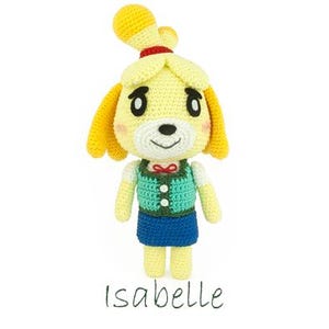May include: A handmade crochet doll of Isabelle from Animal Crossing. The doll has a yellow head with a curled top, a red bow, and a green vest over a white shirt. The doll is wearing a blue skirt. The name "Isabelle" is written below.