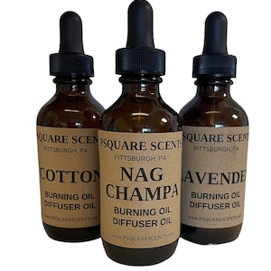 May include: Three amber glass bottles with dropper tops and brown paper labels. The labels read "Square Scents Pittsburgh, PA" and list the scents "Cotton Burning Oil Diffuser Oil", "Nag Champa Burning Oil Diffuser Oil", and "Lavender Burning Oil Diffuser Oil".