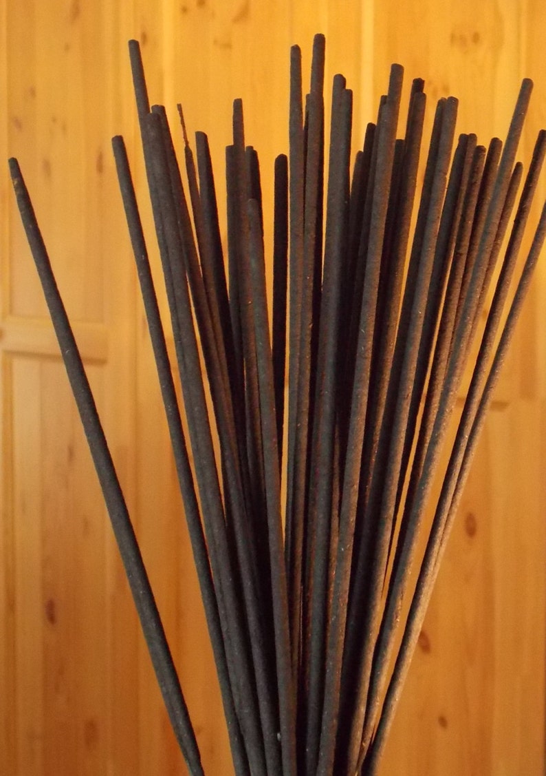 Op de afbeelding: Een bundel bruine wierookstokjes, in een waaier vorm gerangschikt, tegen een houten achtergrond.
