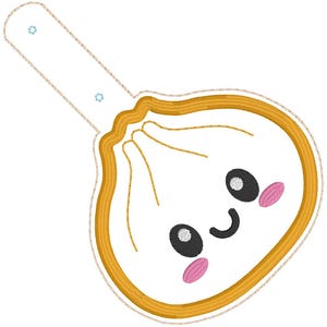 May include: A white embroidered dumpling patch with a golden yellow border and a long tab featuring two small blue eyelets. The dumpling has a smiling face with black oval eyes, a curved black mouth, and two pink oval cheeks stitched onto it.
