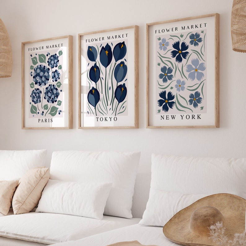 May include: Three framed prints with the title "Flower Market" and the cities "Paris", "Tokyo", and "New York" printed below each image. Each print features a different stylized floral design in shades of blue and green.