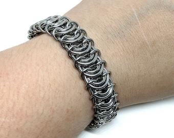May include: A silver chainmail bracelet with a woven design.