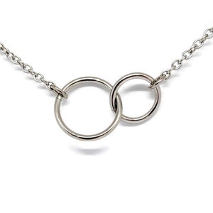 May include: A silver chain necklace with two interlocking circles as a pendant.