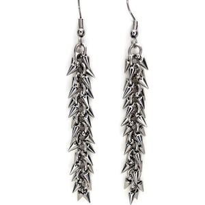 May include: A pair of silver dangle earrings with a chain of small, pointed spikes.
