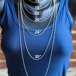 May include: A silver chain necklace is displayed on a mannequin wearing a blue shirt. The necklace is shown in various lengths, from 14 inches to 36 inches.