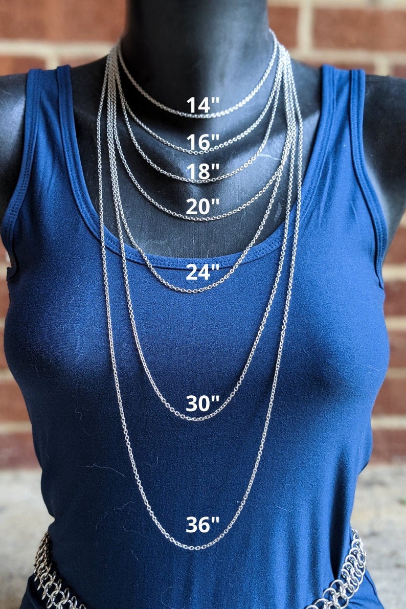 May include: A silver chain necklace is displayed on a mannequin wearing a blue shirt. The necklace is shown in various lengths, from 14 inches to 36 inches.