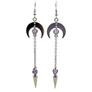 May include: Silver crescent moon earrings with a dangling chain and a purple crystal at the end. The chain has a small purple crystal in the middle.