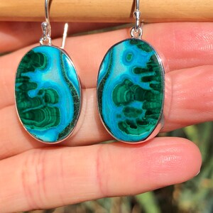 May include: A pair of oval-shaped earrings with green and blue malachite stones set in sterling silver.