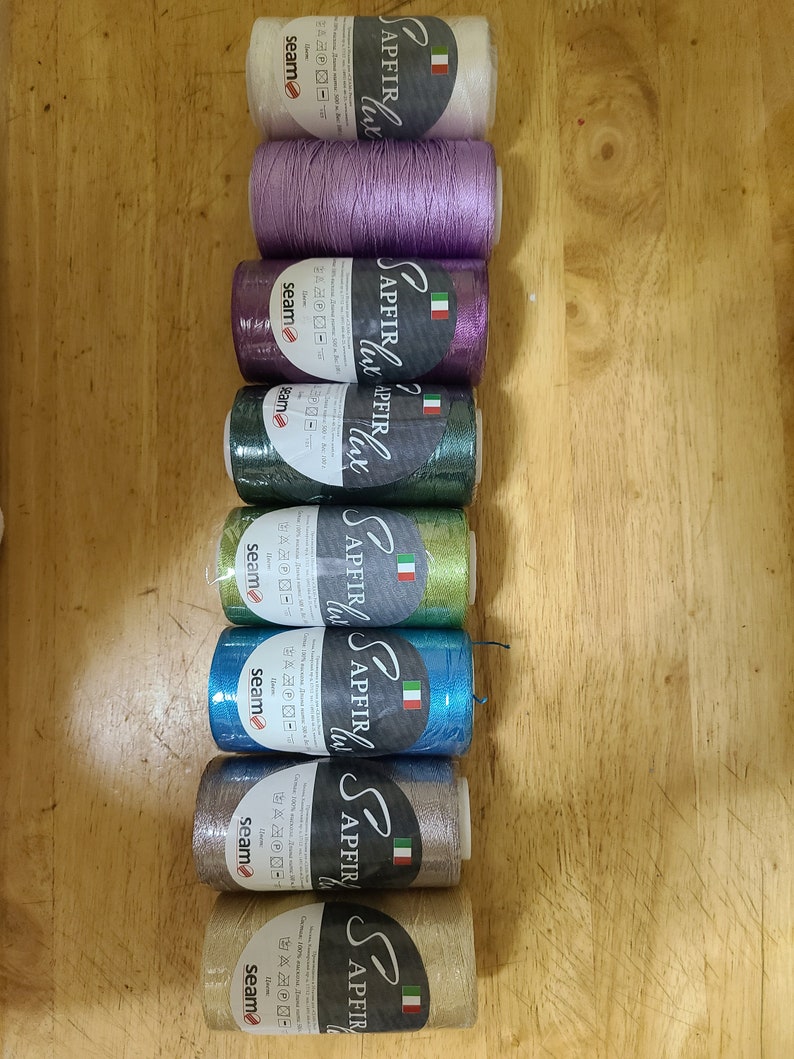 Puede incluir: Ocho carretes de hilo en varios colores, incluyendo blanco, morado, verde, azul, plateado y dorado. Cada carrete tiene el nombre de la marca "SAPFIR" impreso en &eacute;l, junto con el texto "LUCE" y una bandera italiana.