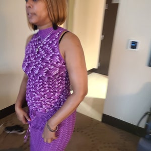 Puede incluir: Una mujer con un vestido sin mangas de color morado y blanco con cuello redondo. El vestido tiene un patr&oacute;n ondulado y una cintura con cord&oacute;n.