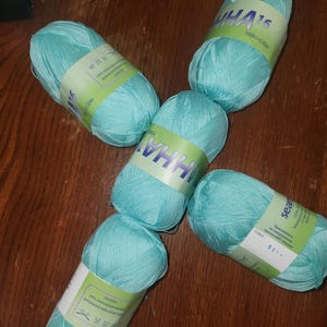 May include: Five skeins of light blue yarn with white labels. The labels have the text "IHA 16" and other text in a foreign language.