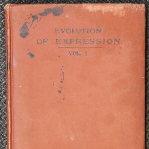 Op de afbeelding: Een bruin lederen gebonden boek met de titel "Evolution of Expression, Vol. I" gedrukt op de voorzijde.