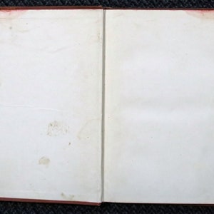 Op de afbeelding: Een leeg, wit boek met een rode kaft. Het boek is open en de pagina's zijn leeg.