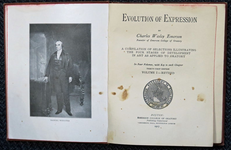 Op de afbeelding: Een zwart-wit portret van Daniel Webster, een prominente Amerikaanse staatsman en redenaar, staat op de linkerpagina. De rechterpagina toont de titel "Evolution of Expression" van Charles Wesley Emerson, oprichter van Emerson College of Oratory. Het boek is een compilatie van selecties die de vier stadia van ontwikkeling in de kunst illustreren, zoals toegepast op de oratoriumkunst. Het is de eenendertigste editie en het eerste deel, dat is herzien.