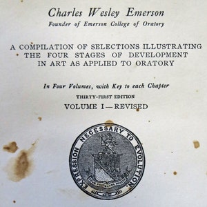 Op de afbeelding: Een zwart-wit afbeelding van een boekomslag voor "Evolution of Expression" door Charles Wesley Emerson, oprichter van Emerson College of Oratory. De boekomslag heeft een zegel met de tekst "Necessary to Evolution" en "Deus Protector Noster". Het boek is in 1917 uitgegeven door Emerson College of Oratory in Boston.