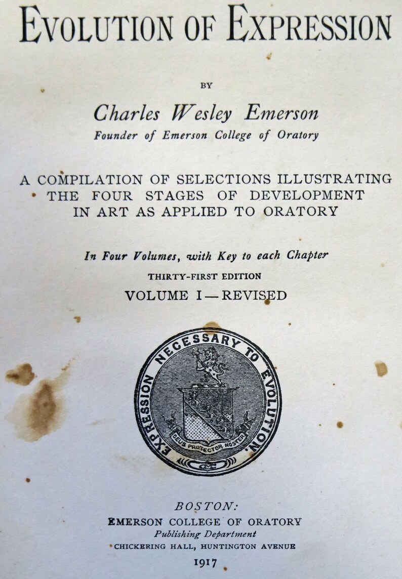Op de afbeelding: Een zwart-wit afbeelding van een boekomslag voor "Evolution of Expression" door Charles Wesley Emerson, oprichter van Emerson College of Oratory. De boekomslag heeft een zegel met de tekst "Necessary to Evolution" en "Deus Protector Noster". Het boek is in 1917 uitgegeven door Emerson College of Oratory in Boston.