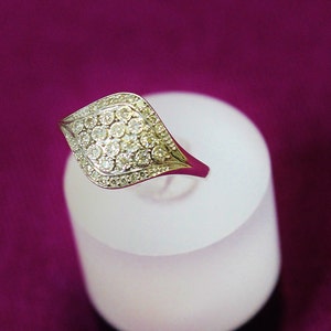 May include: A silver ring with a diamond-shaped setting, featuring a cluster of small, clear diamonds.