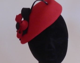 May include: A red felt hat with a black and red flower accent and a black curled feather.