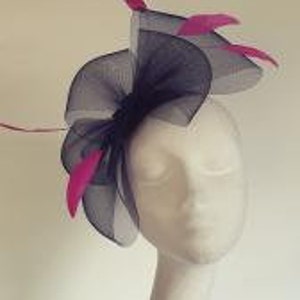 May include: A navy blue and fuchsia feather hair comb with a large, ruffled bow. The comb is made of a delicate mesh fabric and features several long, curled feathers.