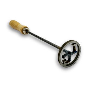 May include: A metal branding iron with a wooden handle. The branding iron has a circular head with a stylized letter "J" design. The handle is light brown, and the metal is a dark gray color.