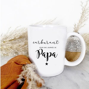Peut inclure: Mug en céramique blanche avec une anse noire et le texte "carburant pour une journée de Papa" avec une étoile noire en dessous du texte.