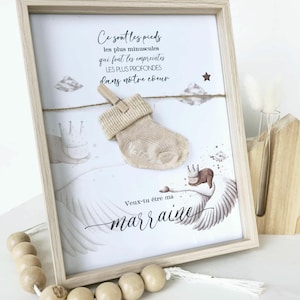 Peut inclure: Cadre en bois clair contenant une œuvre d'art avec un texte en français, une illustration de cygne et une chaussette de bébé beige. Le texte comprend les phrases "Ce sont les pieds" et "Veux-tu être ma marraine."