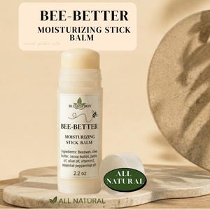 May include: A moisturizing stick balm labeled "BEE-BETTER" with the text "MOISTURIZING STICK BALM". The product is in a white tube with a white cap next to it. The label includes a bee graphic and the words "ALL NATURAL". The product is 2.2 oz.
