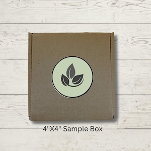 May include: A brown cardboard sample box, 4" x 4", with a circular logo featuring three stylized leaves in a light green circle. The box is centered on a light wood-grain surface.
