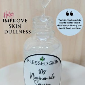 Op de afbeelding: Een heldere glazen fles Blessed Skin 10% Niacinamide Serum met een druppelaar die vloeistof afgeeft. De afbeelding bevat de tekst "Helps Improve Skin Dullness" en een klantcitaat over het product.