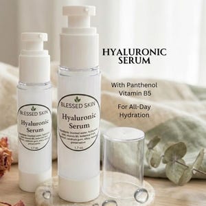 May include: Two white pump bottles of Blessed Skin Hyaluronic Serum with clear caps. The labels state Hyaluronic Serum, With Panthenol Vitamin B5, For All-Day Hydration, and 1.7 oz. The bottles contain a clear liquid and feature a green leaf logo.