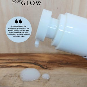 On a wooden background is a sample of the product being pumped out.  The product is white translucent in color and is the consistency of a serum.  The background slogan reads, "Boost your Glow."