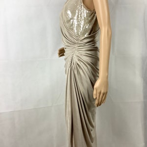 May include: A beige, sleeveless dress with a sequined bodice and draped skirt. The dress is knee-length and has a ruched detail on the side. The dress is displayed on a mannequin.
