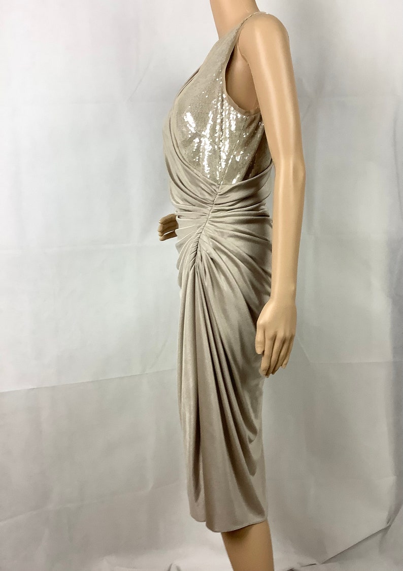 May include: A beige, sleeveless dress with a sequined bodice and draped skirt. The dress is knee-length and has a ruched detail on the side. The dress is displayed on a mannequin.