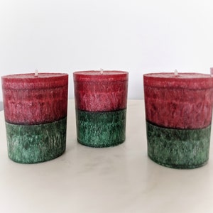 May include: Three red and green pillar candles. The candles are layered with a red top layer and a green bottom layer.