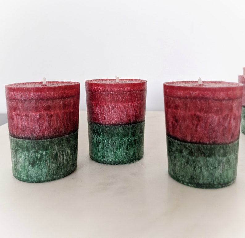 May include: Three red and green pillar candles. The candles are layered with a red top layer and a green bottom layer.