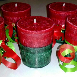 May include: Five red and green candles with a festive ribbon decoration. The candles are red with a green bottom and are decorated with green and red curling ribbon.