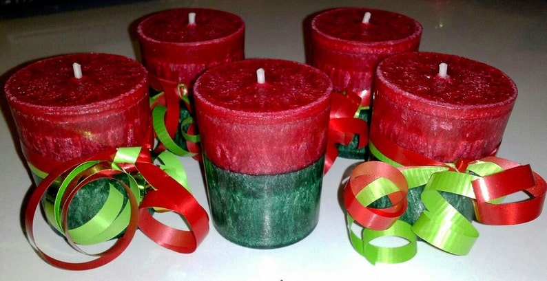 May include: Five red and green candles with a festive ribbon decoration. The candles are red with a green bottom and are decorated with green and red curling ribbon.