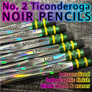 May include: A close-up of several No. 2 Ticonderoga Noir pencils. The pencils have a holographic finish and black wood. Each pencil is labeled with a different name, including Halley, Orion, Apollo, Celeste, Luna, and Neil. The pencils have green and yellow accents and black erasers.