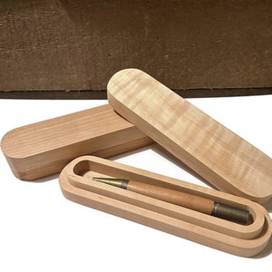May include: A wooden pen case with a lid, the case is open and a wooden pen with a brass tip is inside.