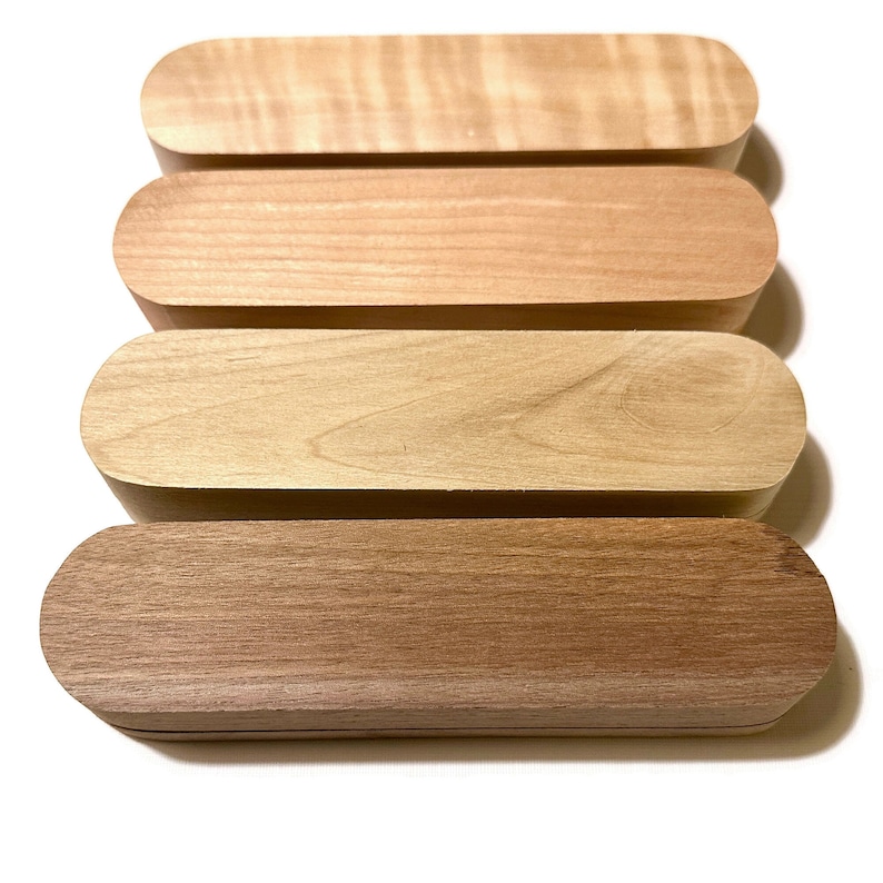 May include: Four wooden boxes stacked on top of each other. The boxes are all made of light wood with a natural finish. The boxes are all the same size and shape, and they are all slightly rounded at the edges.