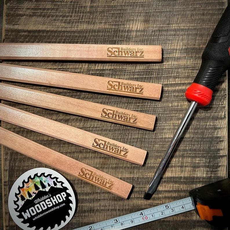 Pu&ograve; includere: Cinque righelli di legno con il testo "Builders Inc. Schwarz" inciso su ciascuno. I righelli sono impilati su una superficie di legno. Nell'immagine sono visibili anche un cacciavite e un metro a nastro.
