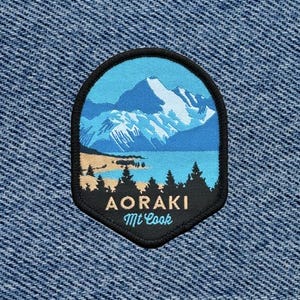 May include: A black and blue embroidered patch with a mountain scene and the text "Aoraki Mt Cook".