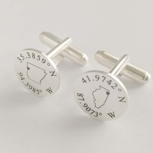 May include: Silver cufflinks with engraved state outlines and coordinates. The left cufflink features Arkansas with the coordinates 35.3859° N 94.3985° W. The right cufflink features Illinois with the coordinates 41.9742° N 87.9073° W.