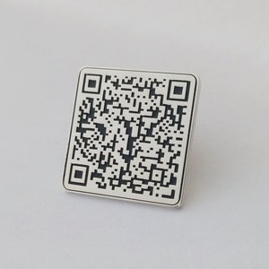May include: A white square with a black and white QR code printed on it.
