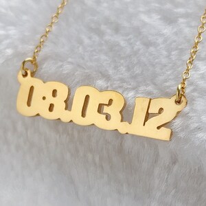 May include: Gold necklace with a pendant featuring the numbers 18.03.12.